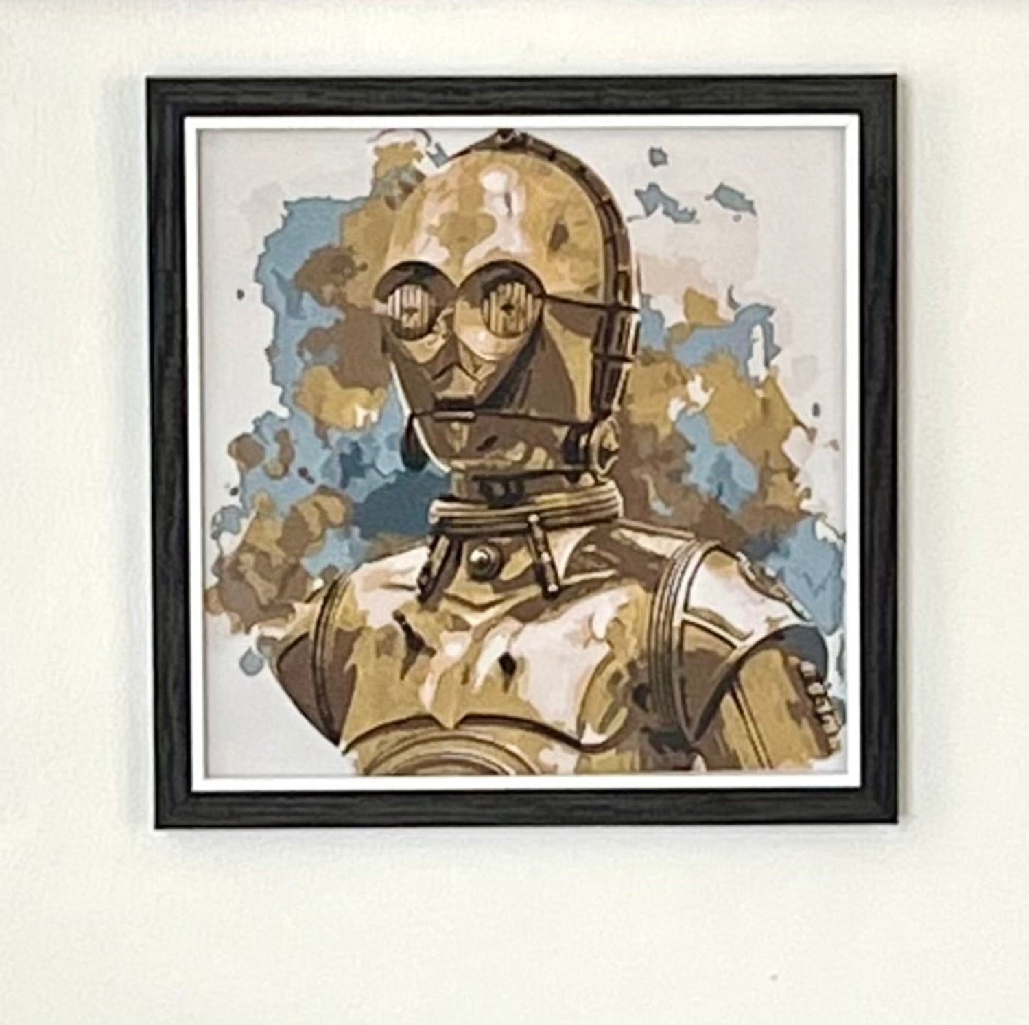 3D Printed Picture of a Popular Gold Robot with a Camouflage Background, Set In a Black Frame