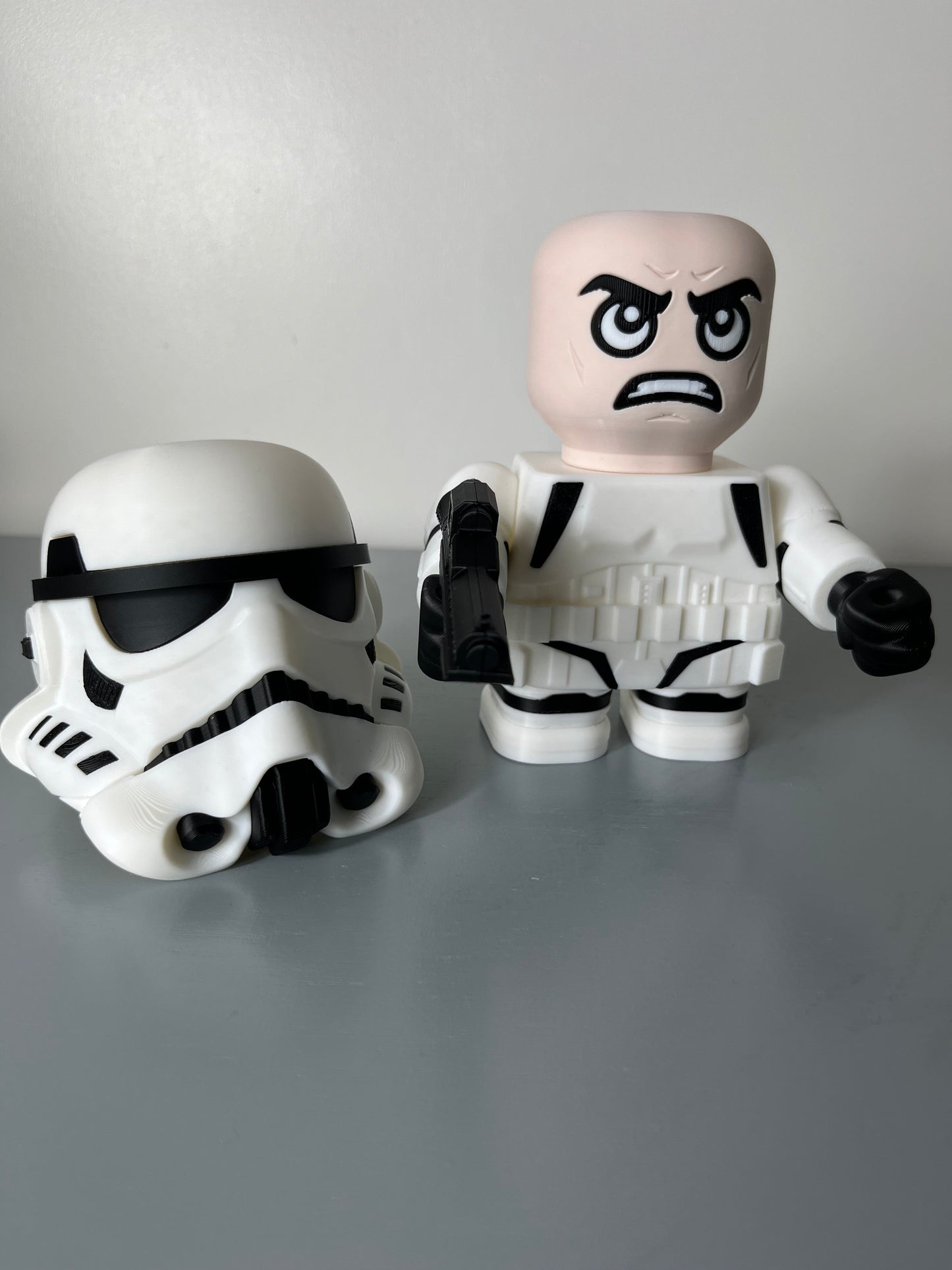 3D printed film character in a white suit with white mask removed and placed on the floor, exposing an angry looking face and holding a gun