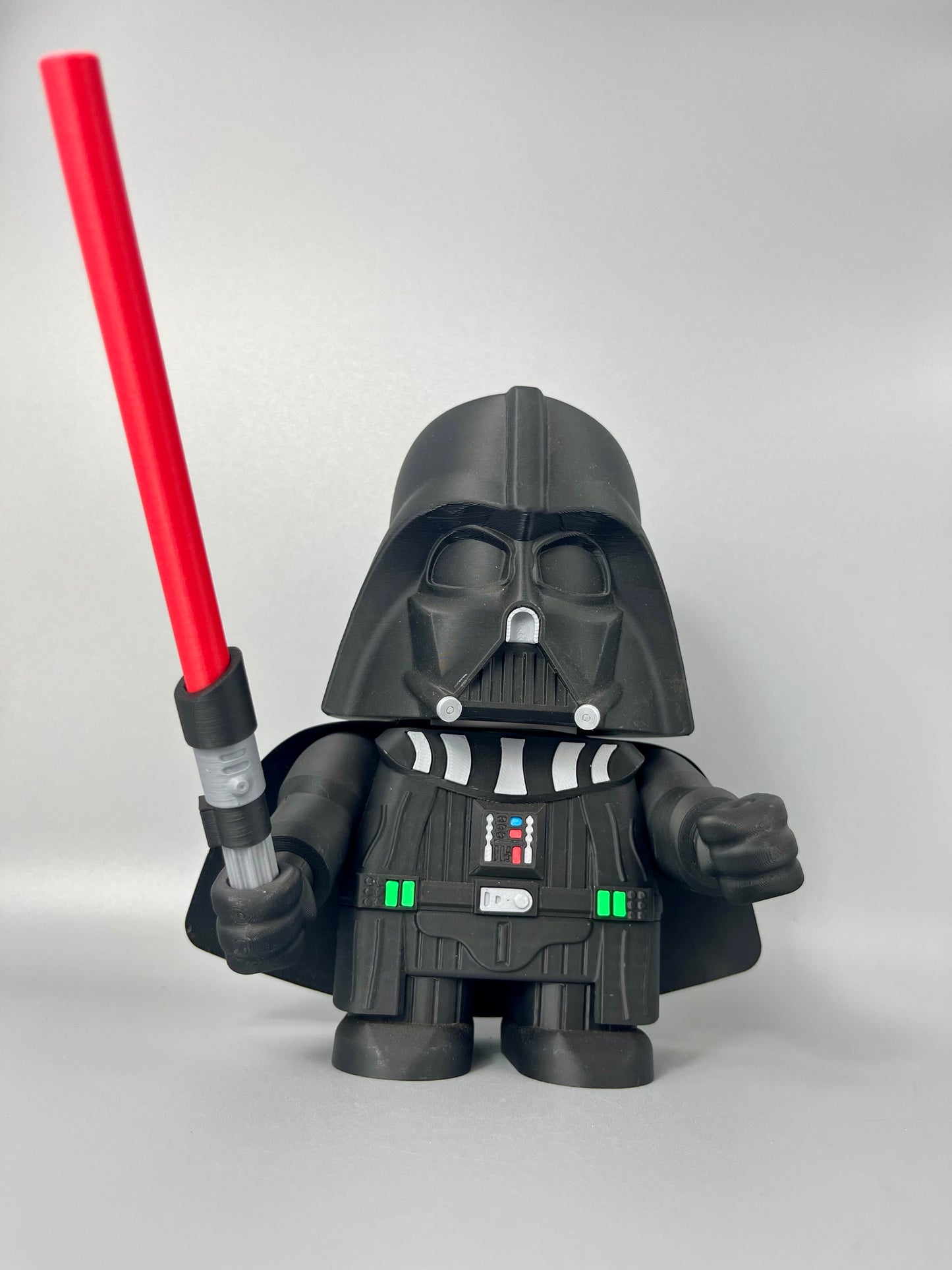 3D printed figure of a character in a black costume, black mask holding a red lightsaber. Standing against a grey background
