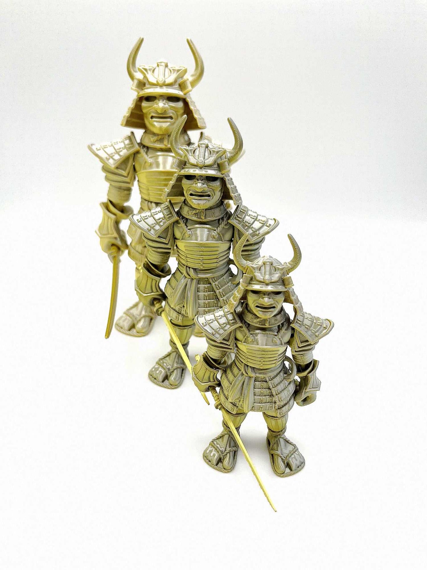 A set of 3 Samurai Warriors (small, medium and large), all 3D printed and wearing traditional Japanese armour and holding a detachable katana sword. Gold and silver in colouring.