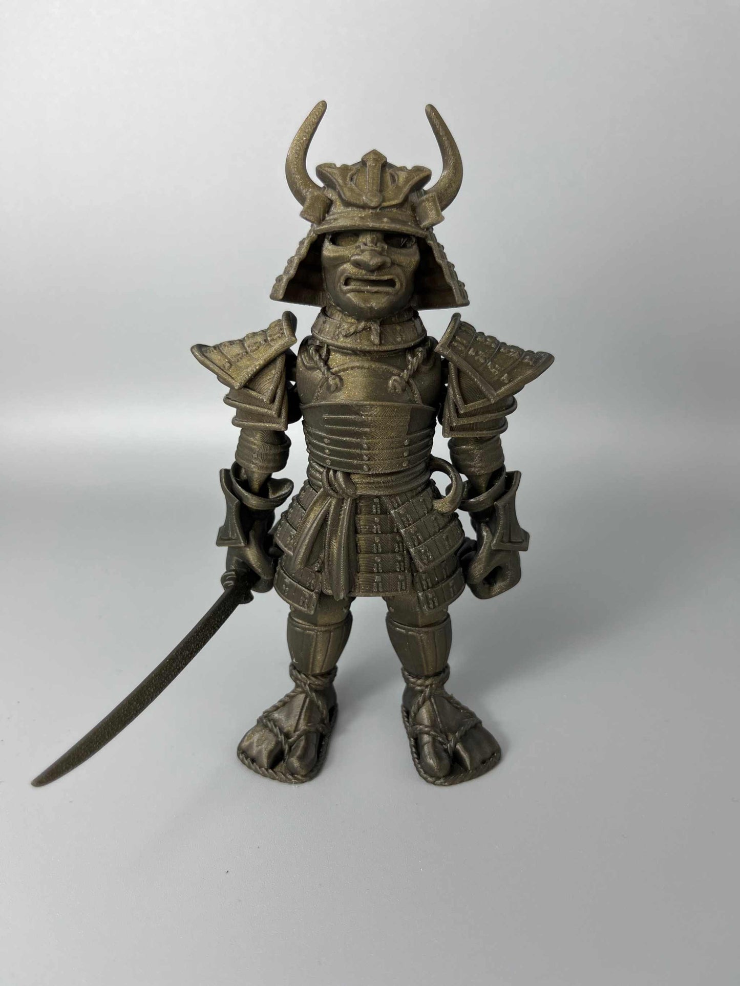A large sized 3D Printed Samurai Warrior, wearing traditional Japanese armour and holding a detachable katana sword. Black and gold in colouring.