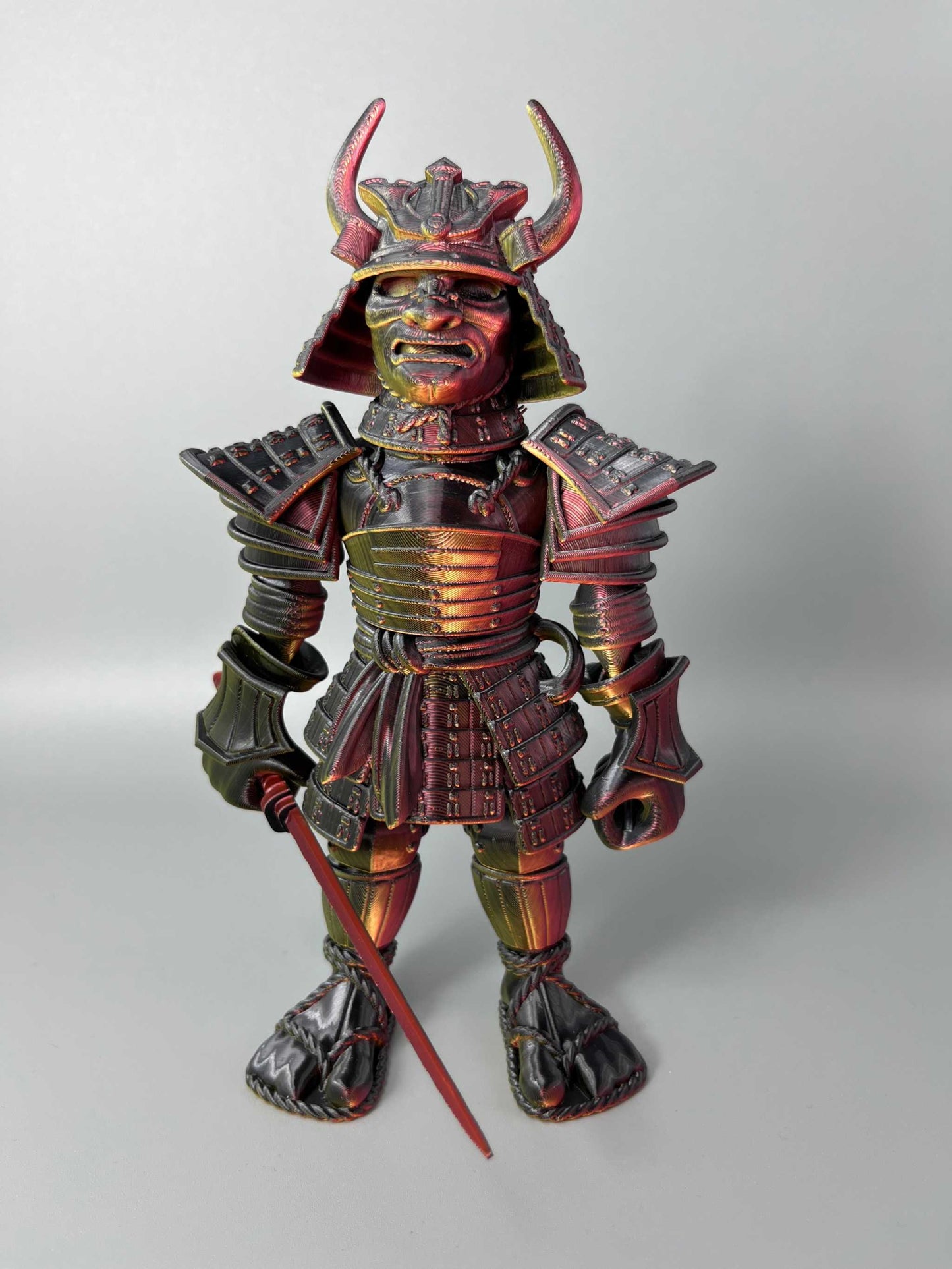A large sized 3D Printed Samurai Warrior, wearing traditional Japanese armour and holding a detachable katana sword. Red, Black and Gold in colouring.