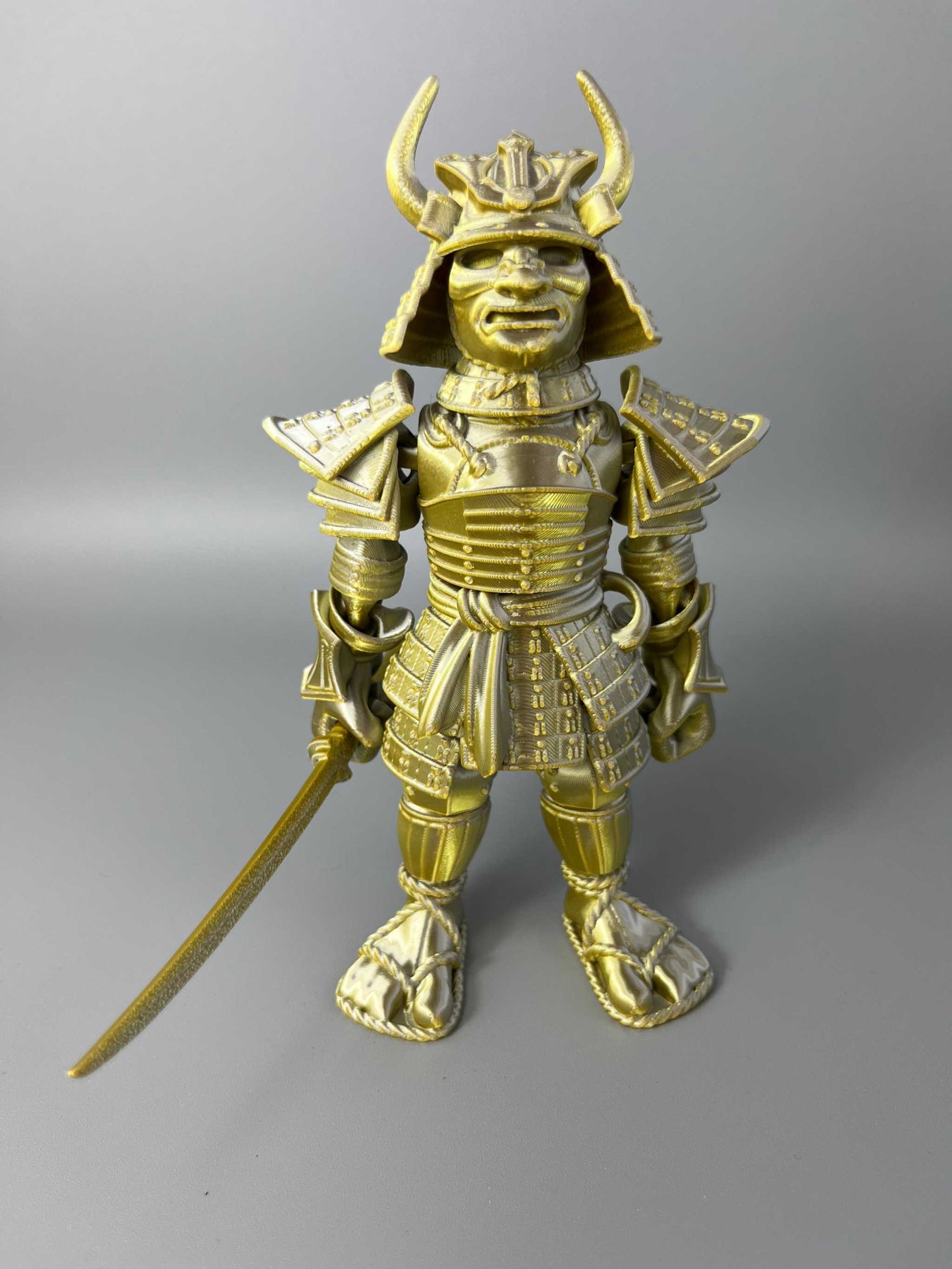 A large sized 3D Printed Samurai Warrior, wearing traditional Japanese armour and holding a detachable katana sword. Gold and Silver in colouring