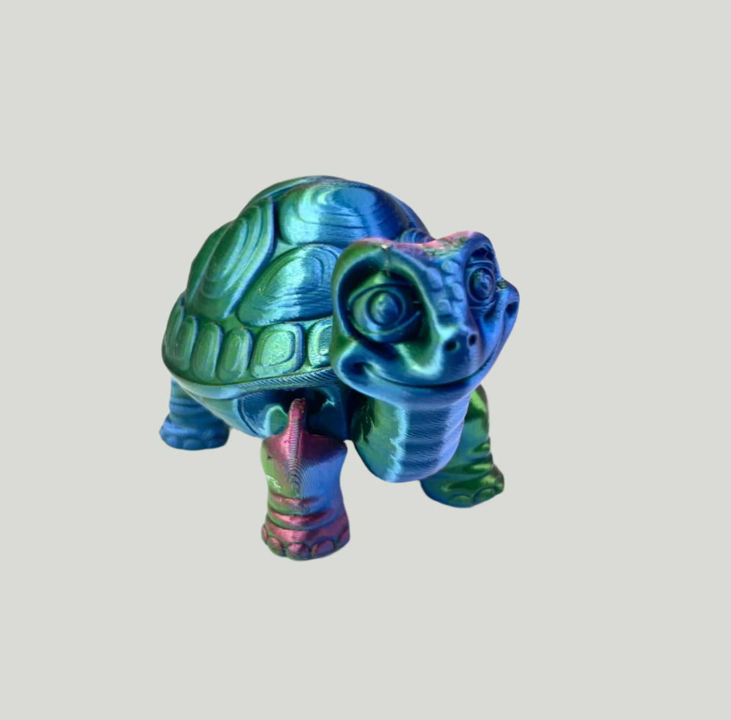 A cute 3D printed shiny blue, green and purple tortoise with detailed face, shell and legs