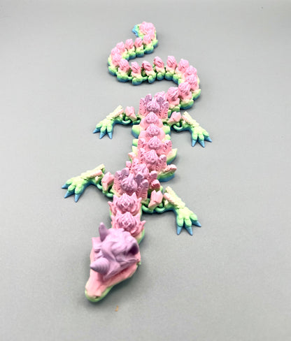 3D Printed dragon with long articulated body and the head of a unicorn, set on a light grey background