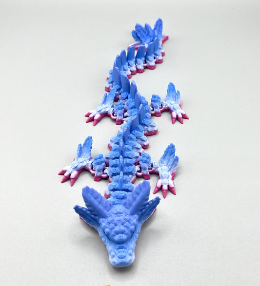A 3D printed blue and pink gradient coloured dragon with a detailed axolotl head. Set on a white background.