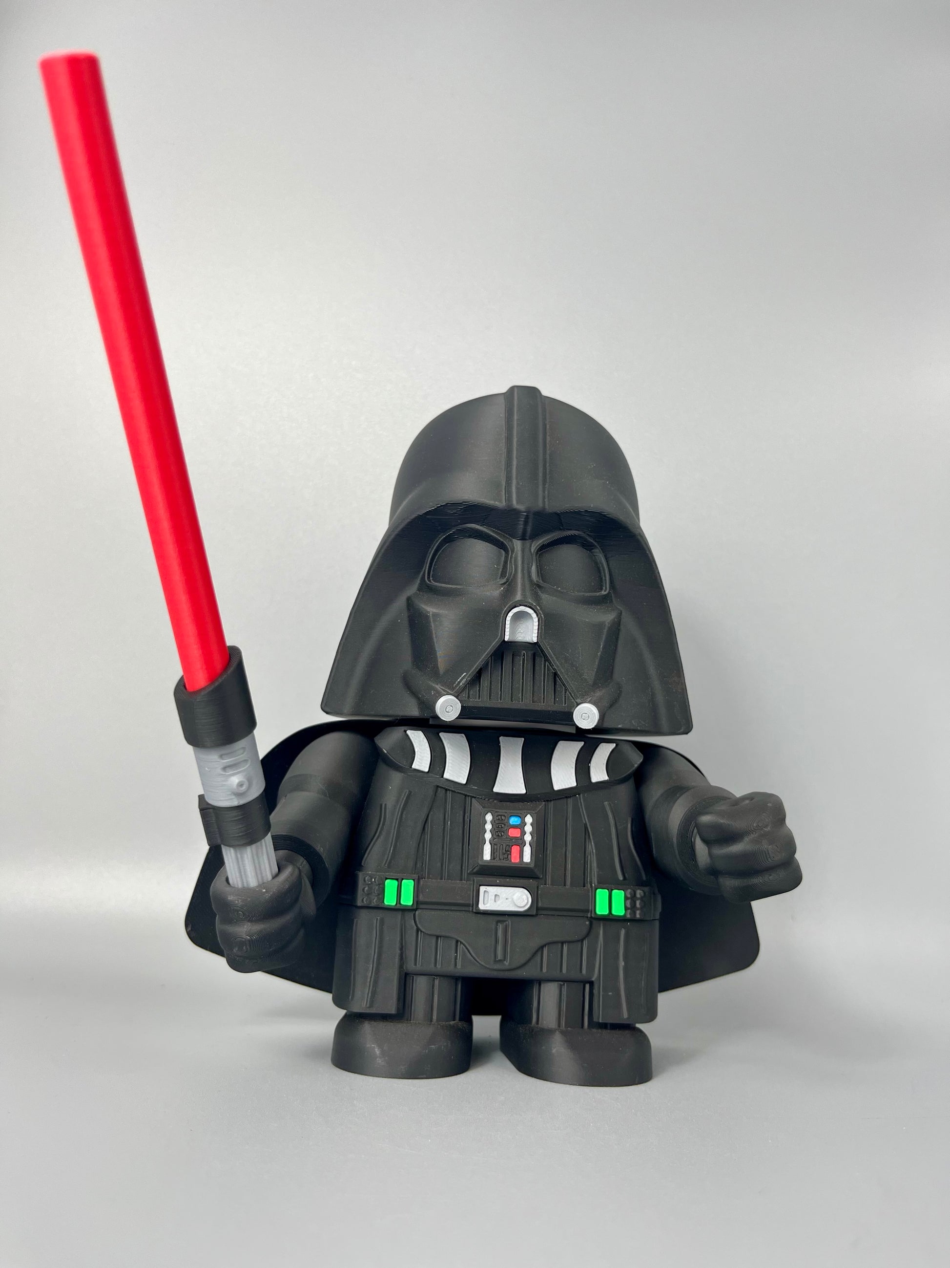 3D printed figure of a character in a black costume, black mask holding a red lightsaber. Standing against a grey background