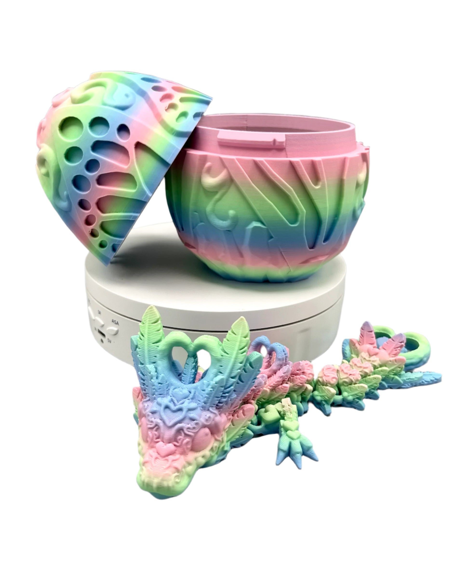 Opened 3D printed rainbow coloured textured dragon egg and matching dragon, laying down, with heart and feather detailing all over from head to tail