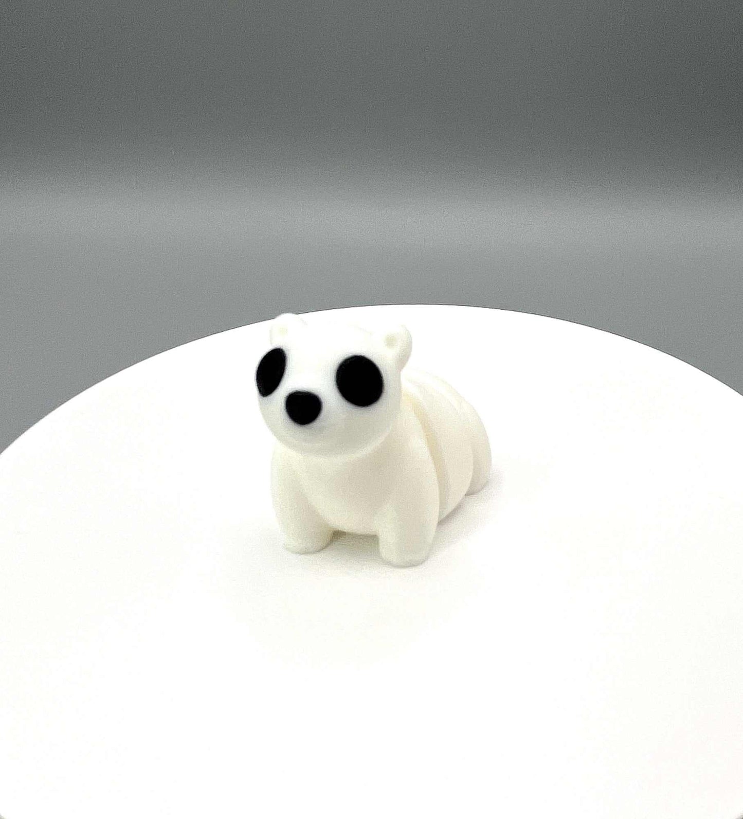 An adorable 3D printed polar bear mini figure with a rounded articulated body, tiny paws, wide eyes and a gentle, curious expression. Perfectly pocket sized!