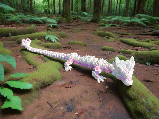 A long, highly detailed 3D printed dragon with pink and white love hearts printed along its articulated body, positioned on moss covered branches in a forest
