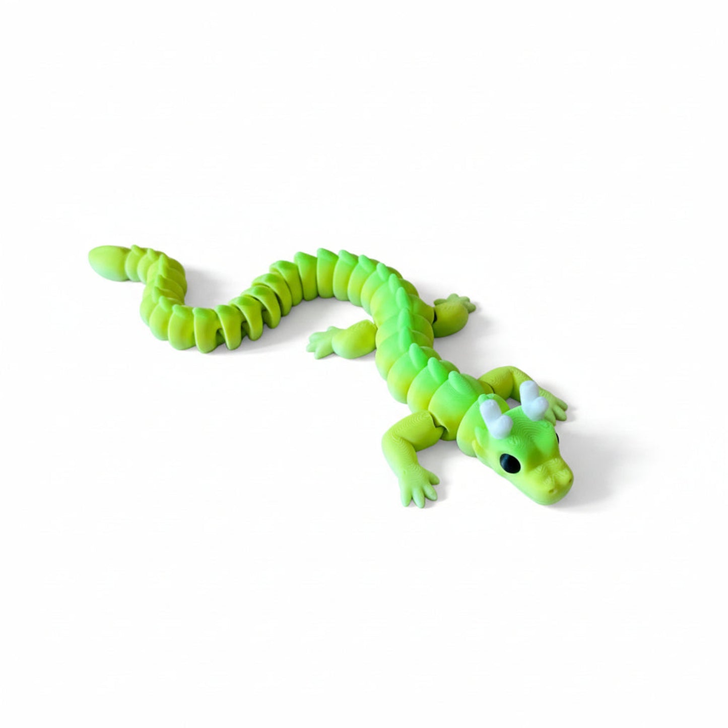 Colourful 3D printed articulated dragon with horns, lying on a white background. It has a flexible, segmented body and moveable little legs.