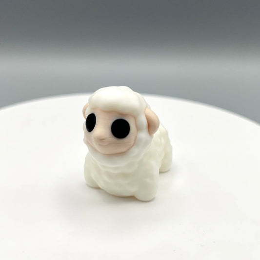 White 3D printed sheep figurine with big black eyes and textured coat. Standing on a white display stand with a grey background