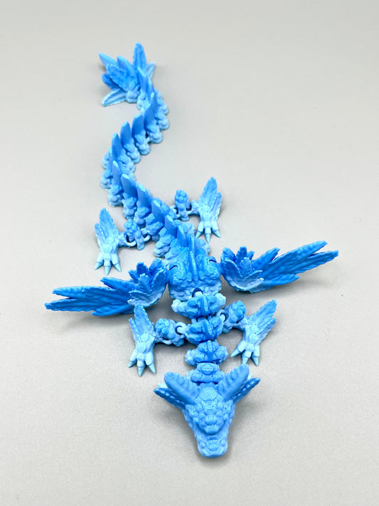 A 3D printed winged dragon in an ice blue gradient colouring, with outstretched wings and an axolotl's head. Set on a light grey background. 