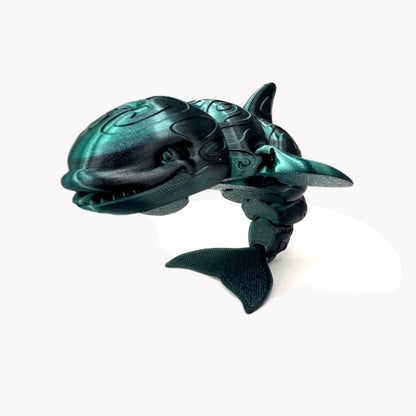 A 3D-printed orca with a tattooed all-over print, detailed facial features, including a smile, exposed teeth and tongue. Positioned standing on it's tail. Set against a white background.