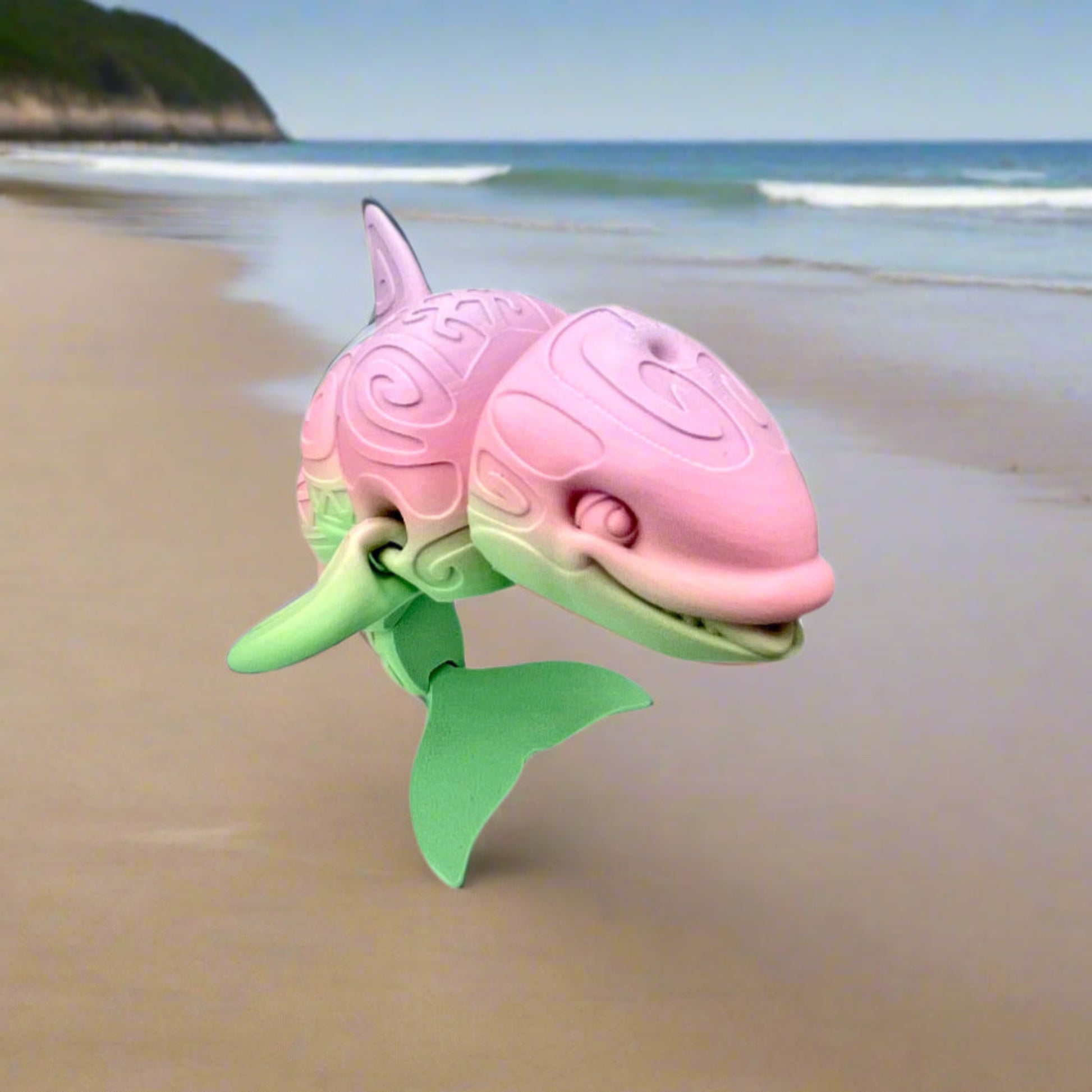 A 3D-printed orca with a tattooed all-over print, detailed facial features, including a smile and exposed teeth and tongue. Positioned standing on it's tail on the beach.