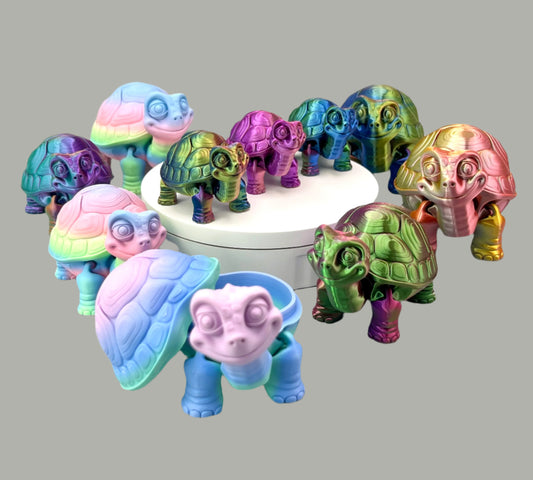 A picture full of cute, multi-coloured 3D printed tortoises, to show the full collection. Some are standing on a white display stand